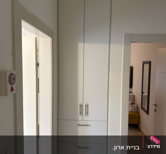 ארון שירות לבן בנוי בנישה עם דלתות ציר ומגירות
